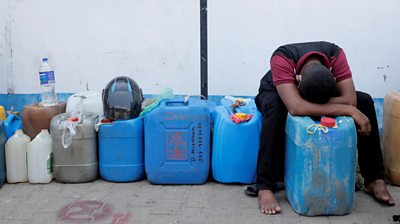 man with head in his hands surrounded by petrol containers