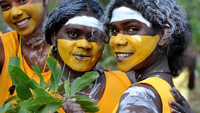 Three young Aboriginal women wearing face paint smiling