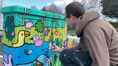 Artist Kev Munday paints a junction box