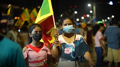 Two women hold a flag at Galle Face protest
