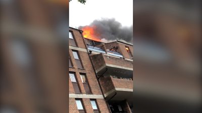 Flames leap from the roof of a block of falts