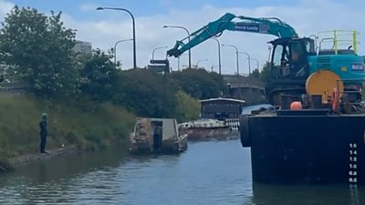 A crane lifts a wreck out of the river