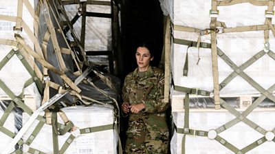 An airman in the cargo bay of a plane carrying baby formula