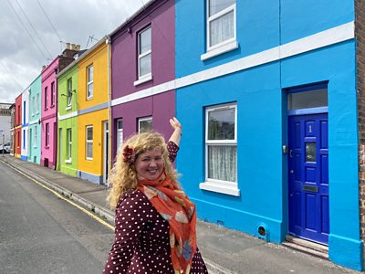 Tash Frootko stands in front of the colourful houses