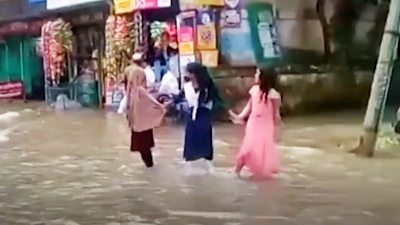 Three young women standing in flood water