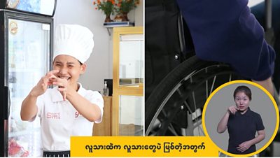 A chef in Myanmar on tv's Media Action's programme Tu Tu Pae which means 'We are the same' - she is wearing a chefs hat, and stripy apron. On the second half of the screen is a wheel of a wheelchair and another lady using sign language.