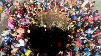 People crowd around a well in India