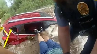 Police pull a woman from a flooded car