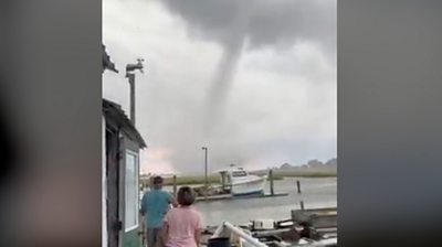 People stand on a dock, looking at the waterspout
