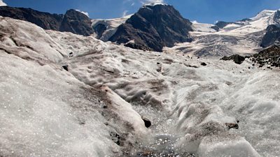 Meltwater flows into an ice crevice at the Pers Glacier in Switzerland