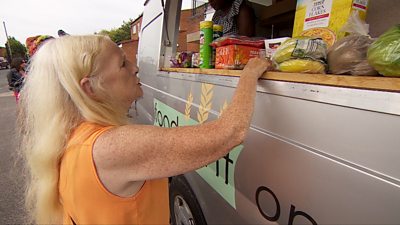 A woman buys some groceries from the mobile supermarket