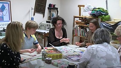 Group of women sat around table making quilt