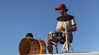A drummer performs on the roof of his van
