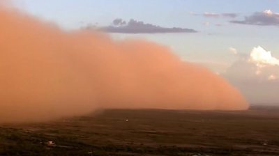 Orange dust cloud sweeping across ground