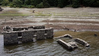 Stone house partially submerged near the shore of a reservoir