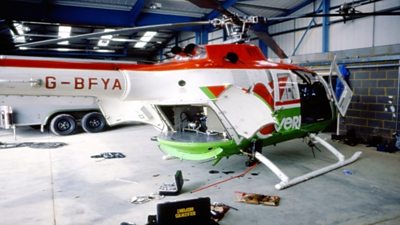 A helicopter in a hangar with an open platform on which is various equipment