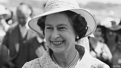 Queen Elizabeth II pictured in black and white smiling at a horse race in 1980