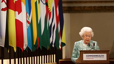 Queen Elizabeth II giving a Commonwealth speech next to the nation flags