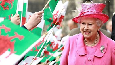 The Queen walks through a sea of Welsh flags