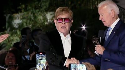 A surprised Sir Elton John receives an award after performing at the White House