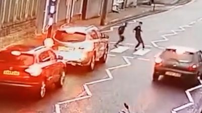 Driver overtakes vehicles while children are walking across a zebra crossing