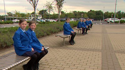 Six sets of twins sitting on benches