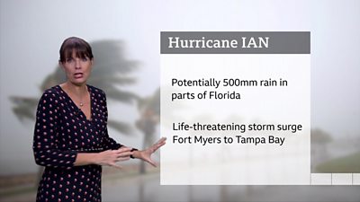 Susan Powell in front of a screen showing the potential impacts of Hurricane Ian