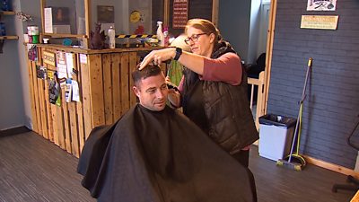 Man getting haircut from woman in a barbers shop