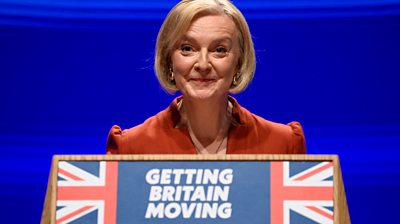 UK Prime Minister Liz Truss on stage in front of a lectern that says 'getting Britain moving'