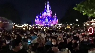 Mask wearing crowds in front of iconic Disney castle