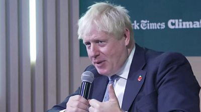 Boris Johnson holding a microphone while speaking at an event in Egypt