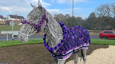 Horse statue dressed in coat of purple poppies