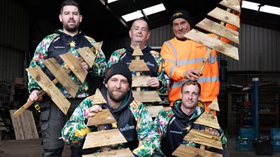 Reese and his team posing with wooden Christmas trees