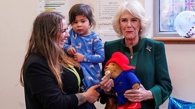 Camilla, the Queen Consort, holding a Paddington Bear toy and a marmalade sandwich