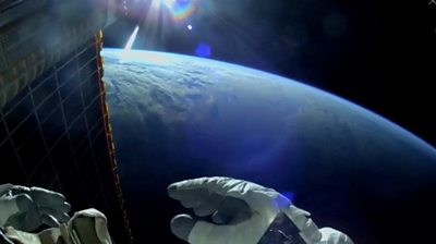An astronaut's hand in from of the Earth from above