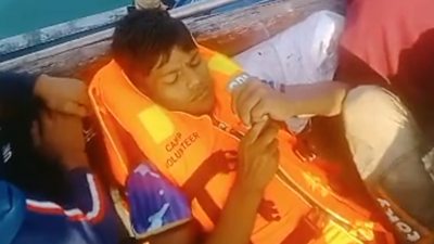 Rohingya refugee lying on a boat wearing a life jacket