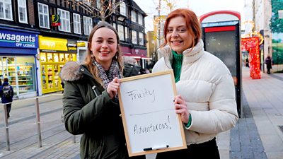 Two women holding a whiteboard with the words "Fruity" and "Adventurous"