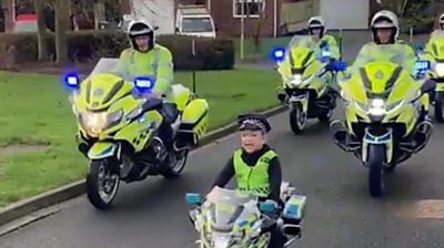 Harry riding his bike alongside police officers on motorbikes
