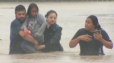 People wading through flood waters in