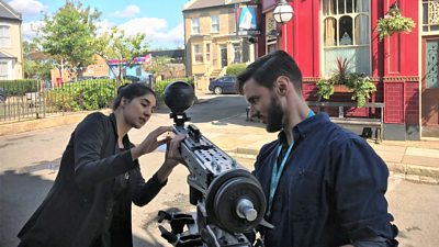 Two people adjust a special camera capturing footage on the EastEnders set outside the Queen Vic pub.