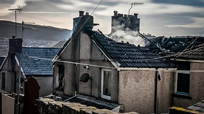 Burnt out roof of a home still smouldering