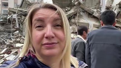 BBC Correspondent Anna Foster standing in front of rubble of collapsed building