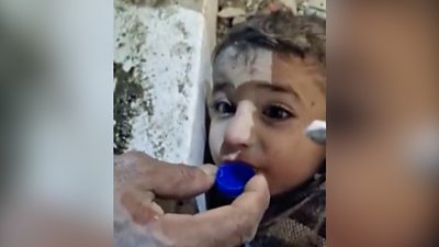 Little boy trapped in rubble drinks from a bottle cap
