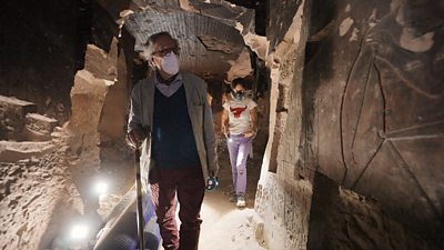 A man wearing a mask explores a tomb