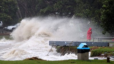 Woman in raincoat hit by large wave