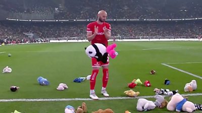 A footballer standing in front of a falling soft panda toy