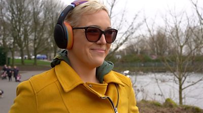 Lauren walking through park wearing headphones