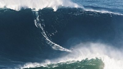 Surfer rides as big wave looms overhead