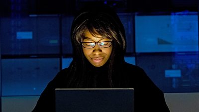 A woman looking at a laptop screen in a darkened room