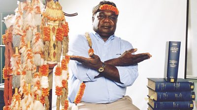 Yunupingu poses with symbols of Aboriginal law and acts of parliament